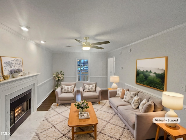 living area featuring crown molding, a ceiling fan, a fireplace, and wood finished floors