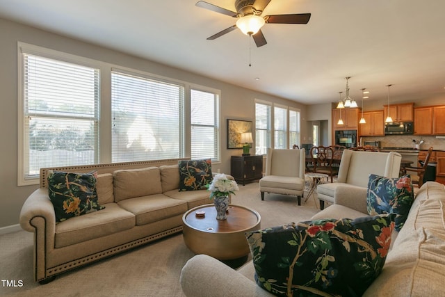 living room featuring baseboards, a ceiling fan, and light colored carpet