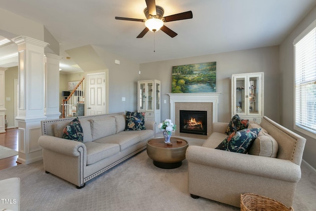 living room with stairs, ceiling fan, a glass covered fireplace, and ornate columns