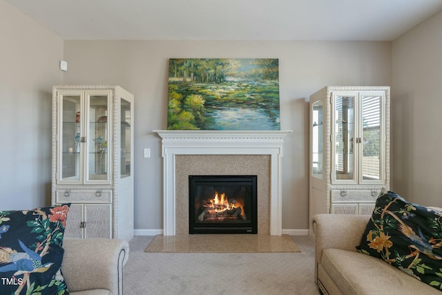 living room featuring a glass covered fireplace, baseboards, and carpet