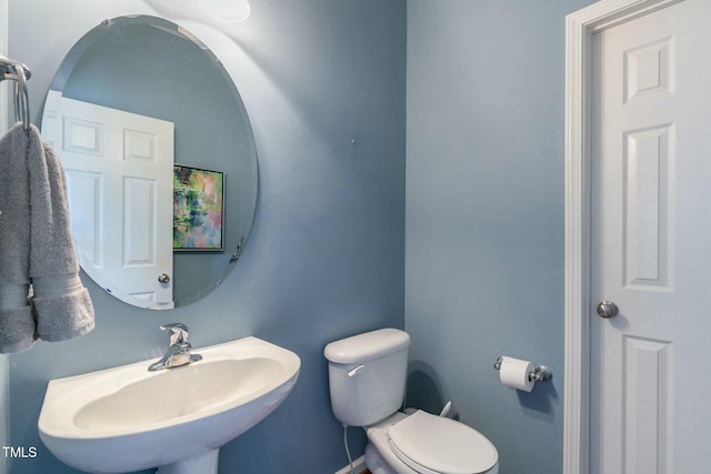 half bath featuring toilet and a sink