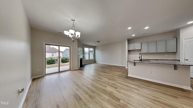 unfurnished living room with sink, a chandelier, and light wood-type flooring