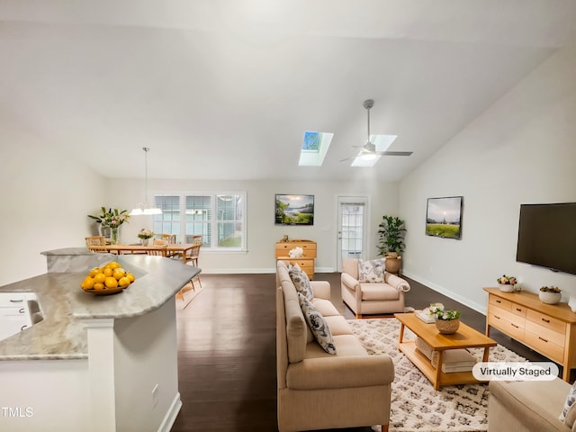 living room featuring dark wood-type flooring, lofted ceiling with skylight, and ceiling fan