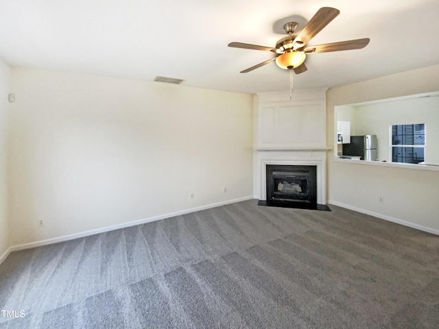 unfurnished living room with a large fireplace, carpet flooring, a ceiling fan, visible vents, and baseboards