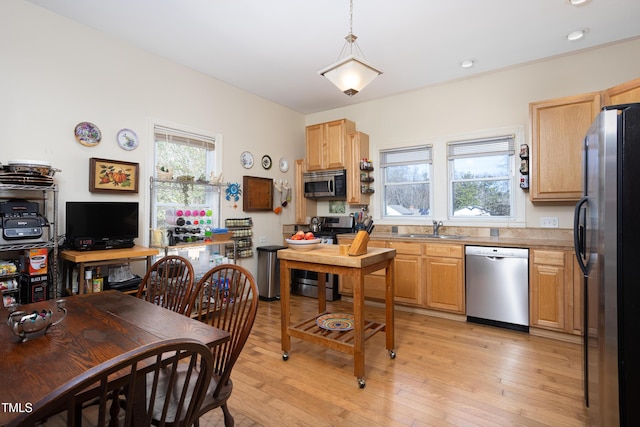 kitchen with appliances with stainless steel finishes, light hardwood / wood-style floors, sink, and a wealth of natural light