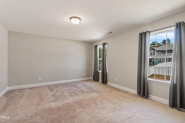 spare room featuring light colored carpet and a healthy amount of sunlight