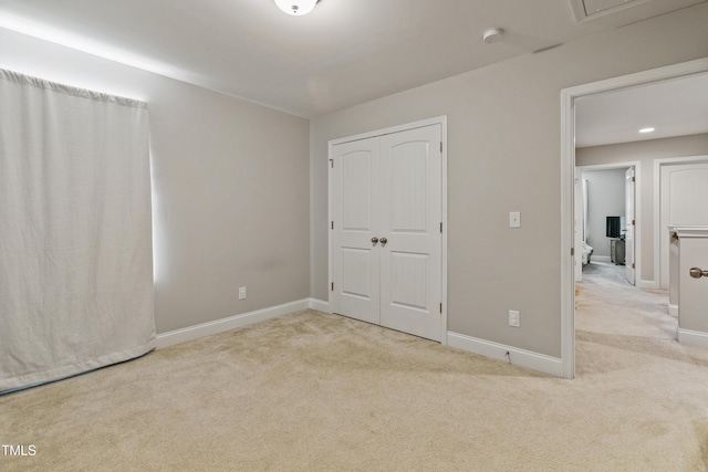 unfurnished bedroom with light colored carpet and a closet
