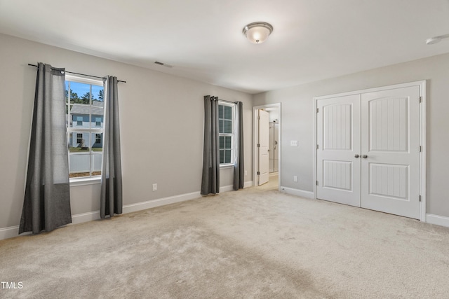 unfurnished bedroom with light colored carpet and a closet