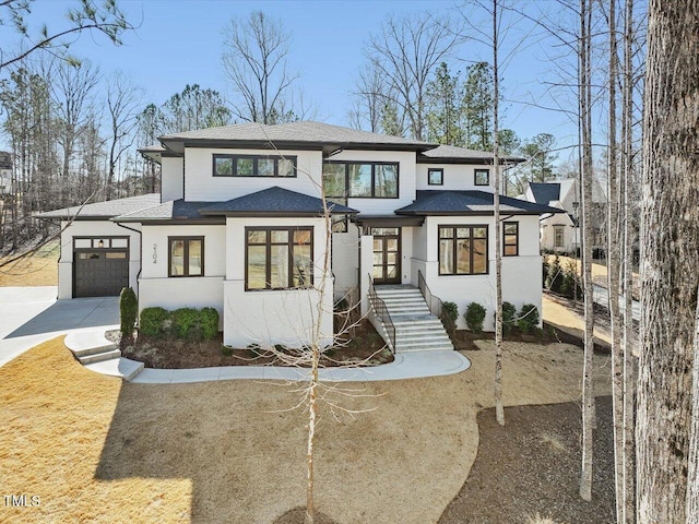 prairie-style home with an attached garage, a shingled roof, and concrete driveway