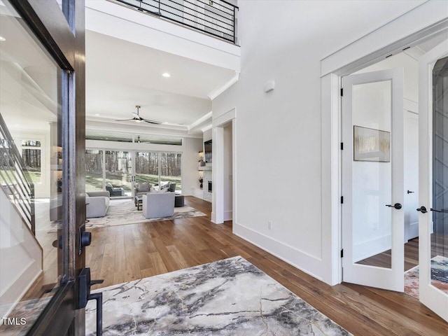 entrance foyer featuring crown molding, wood finished floors, a ceiling fan, and baseboards