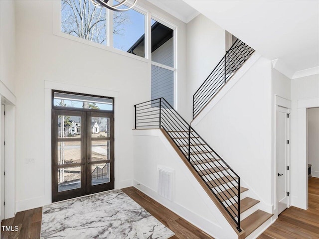 foyer featuring baseboards, visible vents, dark wood-type flooring, a high ceiling, and crown molding