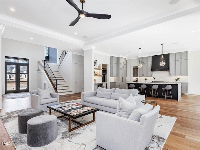 living room with stairway, a raised ceiling, light wood-style flooring, and recessed lighting