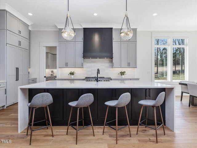 kitchen featuring gray cabinetry, tasteful backsplash, a large island with sink, and custom range hood