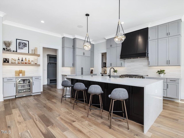 kitchen featuring wine cooler, a large island, light countertops, gray cabinetry, and premium range hood