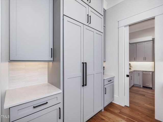 kitchen featuring tasteful backsplash, dishwasher, gray cabinetry, and wood finished floors