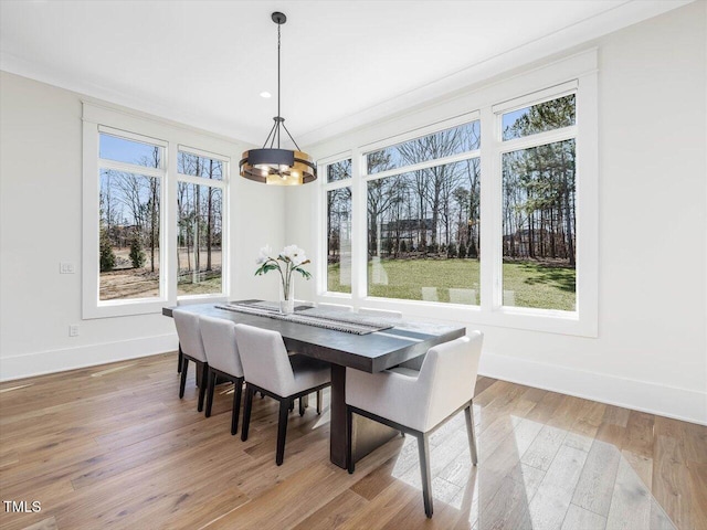 dining room with ornamental molding, a chandelier, light wood-style flooring, and baseboards