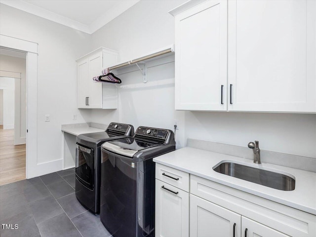 washroom with a sink, baseboards, washer and dryer, cabinet space, and crown molding