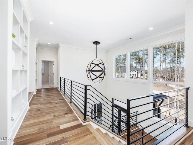 hall featuring recessed lighting, an inviting chandelier, ornamental molding, an upstairs landing, and wood finished floors