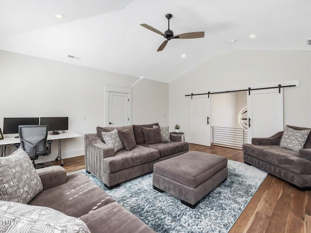 living room with a barn door, wood finished floors, visible vents, a ceiling fan, and vaulted ceiling