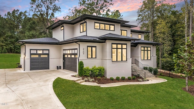 prairie-style home featuring a garage, a shingled roof, concrete driveway, a front lawn, and brick siding