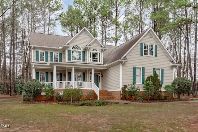 view of front facade with covered porch, a front lawn, and a shingled roof