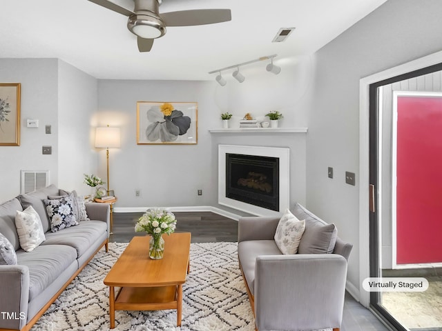 living area with ceiling fan, a fireplace, wood finished floors, visible vents, and baseboards