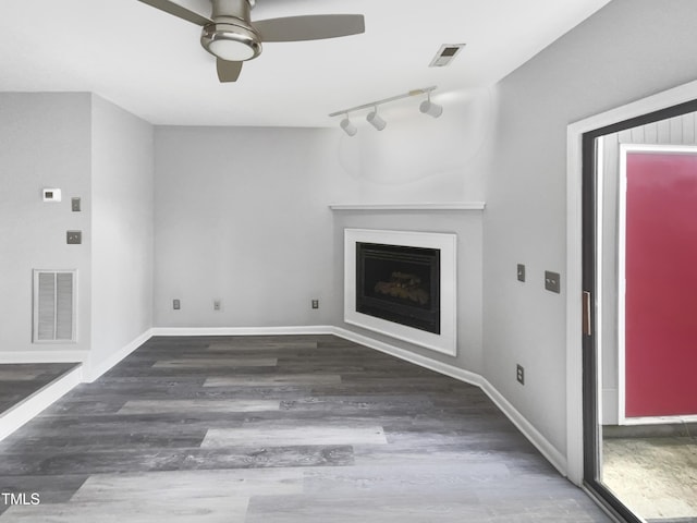 unfurnished living room featuring baseboards, visible vents, ceiling fan, dark wood-type flooring, and a fireplace