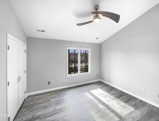 unfurnished bedroom with lofted ceiling, dark wood-type flooring, ceiling fan, and a closet