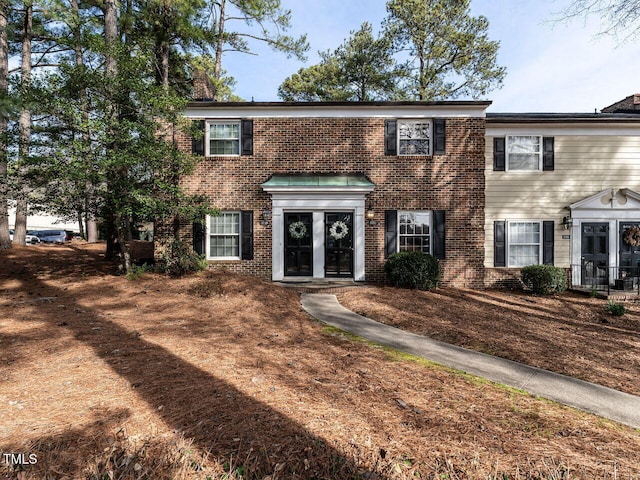 colonial inspired home featuring french doors and brick siding