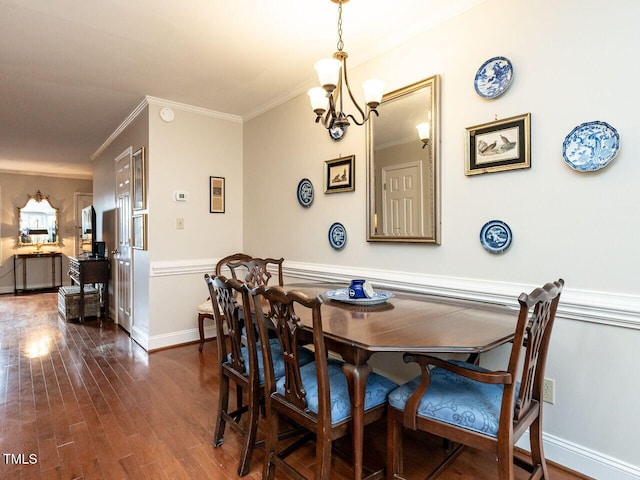 dining space featuring dark wood-style floors, ornamental molding, baseboards, and an inviting chandelier