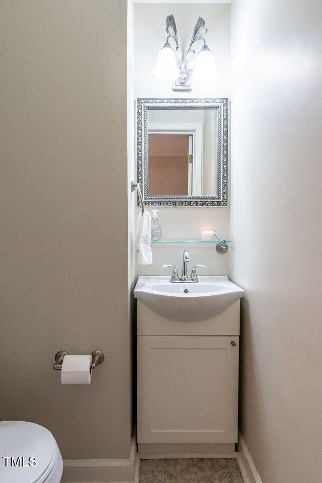 bathroom featuring toilet, tile patterned floors, baseboards, and vanity