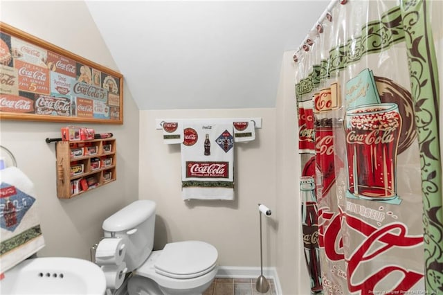 bathroom featuring tile patterned flooring, lofted ceiling, and toilet