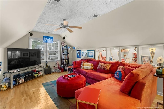 living room with ceiling fan, wood-type flooring, vaulted ceiling, and a textured ceiling