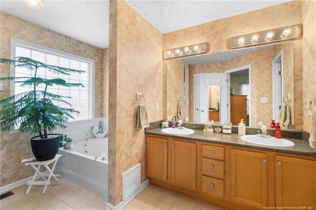 bathroom with tile patterned flooring, vanity, a tub, and a textured ceiling