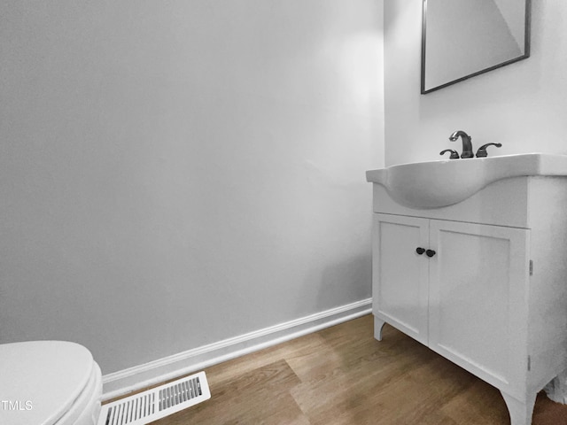 bathroom with wood-type flooring, vanity, and toilet