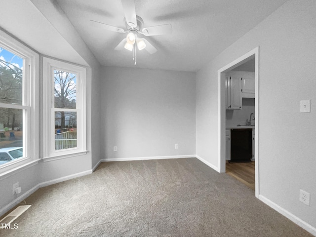 unfurnished room with ceiling fan, carpet flooring, and sink