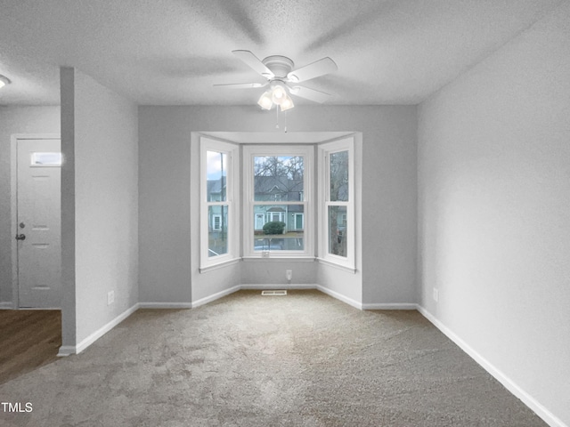 carpeted spare room with ceiling fan and a textured ceiling