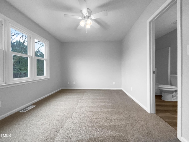 unfurnished bedroom with ceiling fan, ensuite bath, and carpet floors