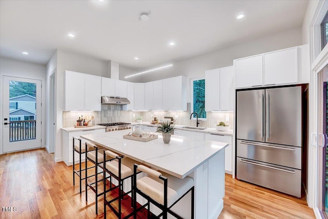 kitchen featuring sink, white cabinets, a kitchen bar, a center island, and stainless steel appliances