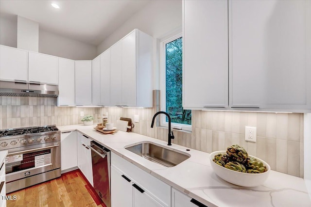 kitchen with tasteful backsplash, appliances with stainless steel finishes, sink, and white cabinets