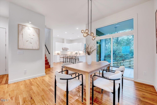 dining space with a notable chandelier and light hardwood / wood-style flooring