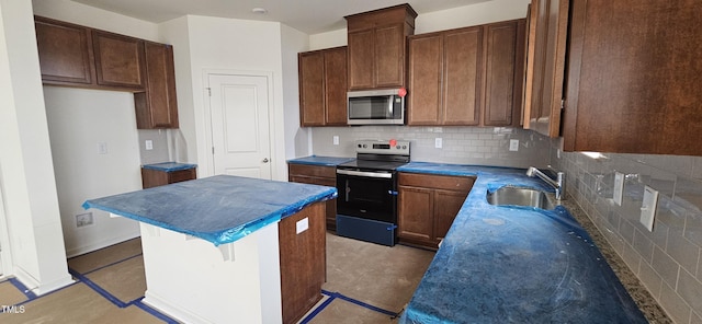 kitchen featuring appliances with stainless steel finishes, sink, a kitchen island, and backsplash