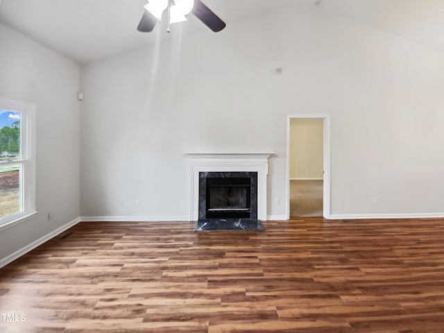 unfurnished living room with hardwood / wood-style floors, high vaulted ceiling, a premium fireplace, and ceiling fan