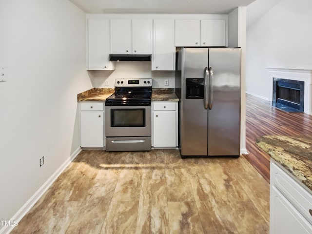 kitchen with appliances with stainless steel finishes, white cabinets, a high end fireplace, and dark stone counters