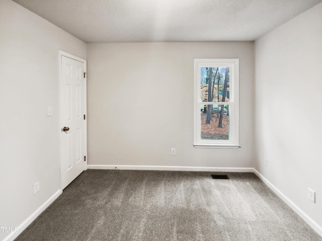 empty room with a textured ceiling and dark colored carpet