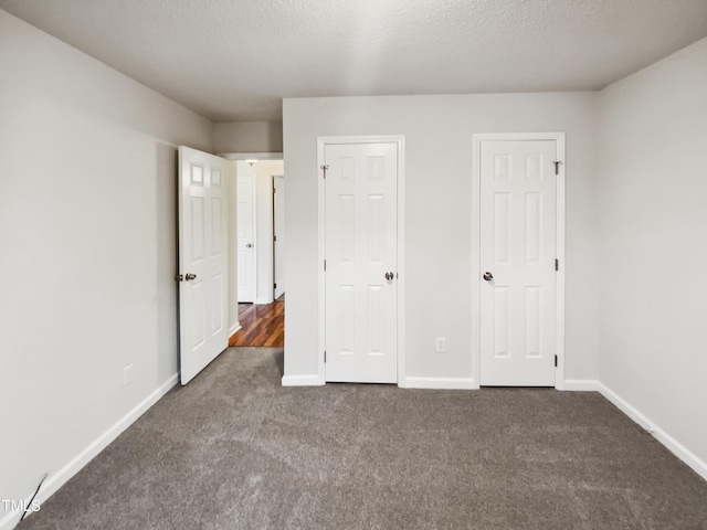 unfurnished bedroom featuring a textured ceiling and dark carpet