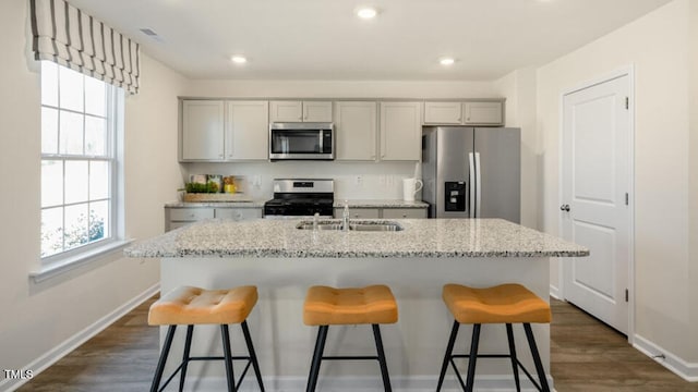 kitchen with gray cabinetry, sink, light stone countertops, and appliances with stainless steel finishes