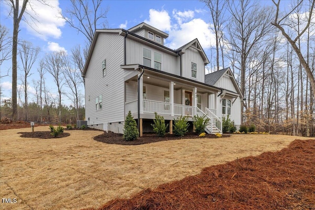 view of front of house with central AC, covered porch, and a front lawn