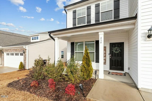 view of exterior entry featuring a porch, driveway, and a garage