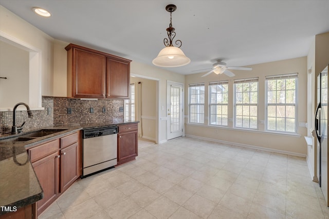 kitchen featuring pendant lighting, sink, dark stone countertops, backsplash, and stainless steel dishwasher